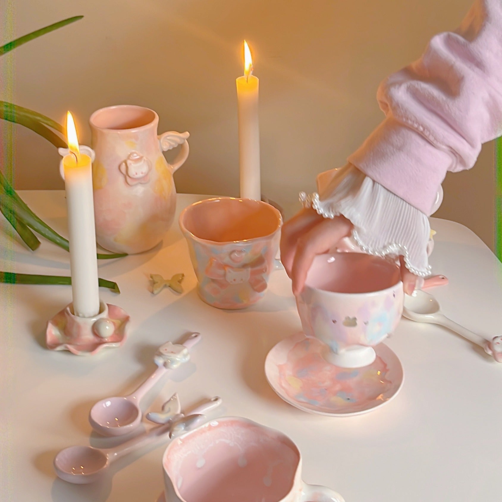 Handmade ceramic vase, cups, spoon, plate and candle holders arranged on a table.